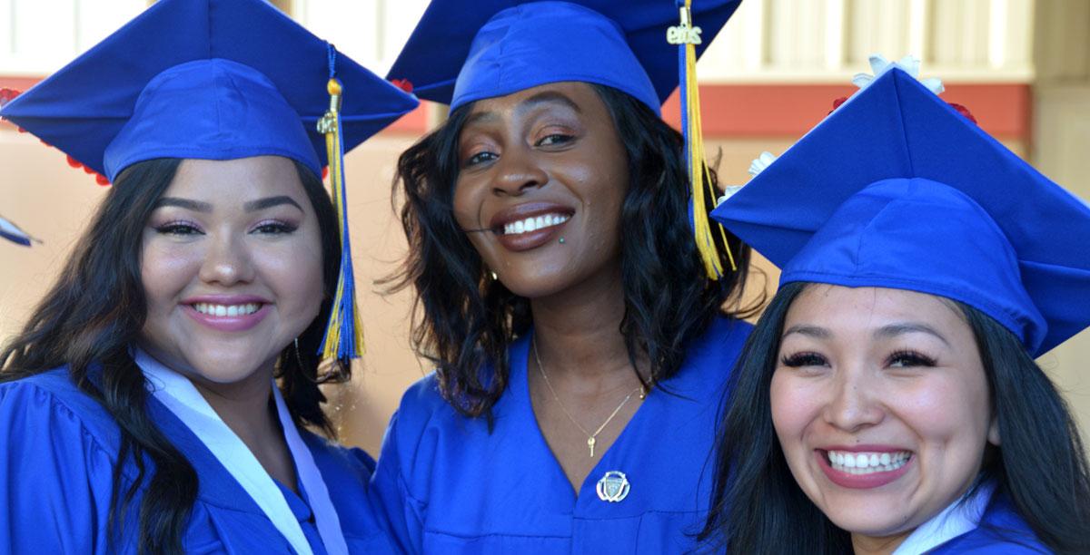 Female 博天堂官方 students in blue cap and gown smiling at camera