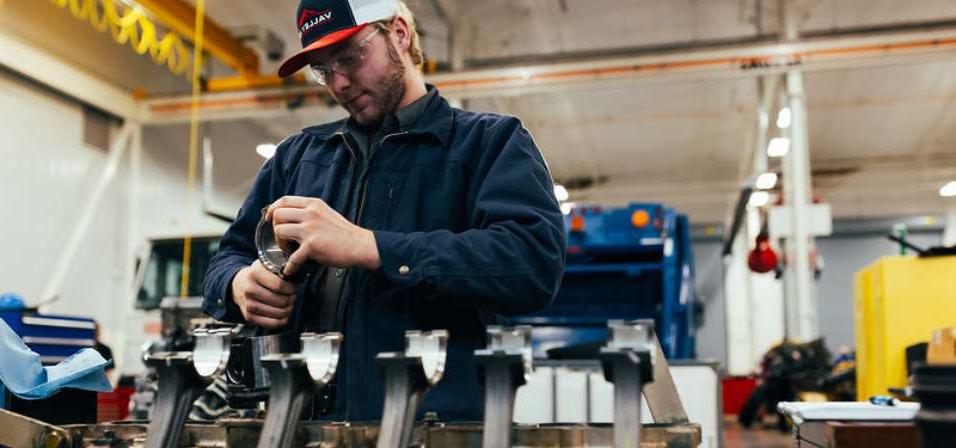 A student in the heavy equipment building holding parts