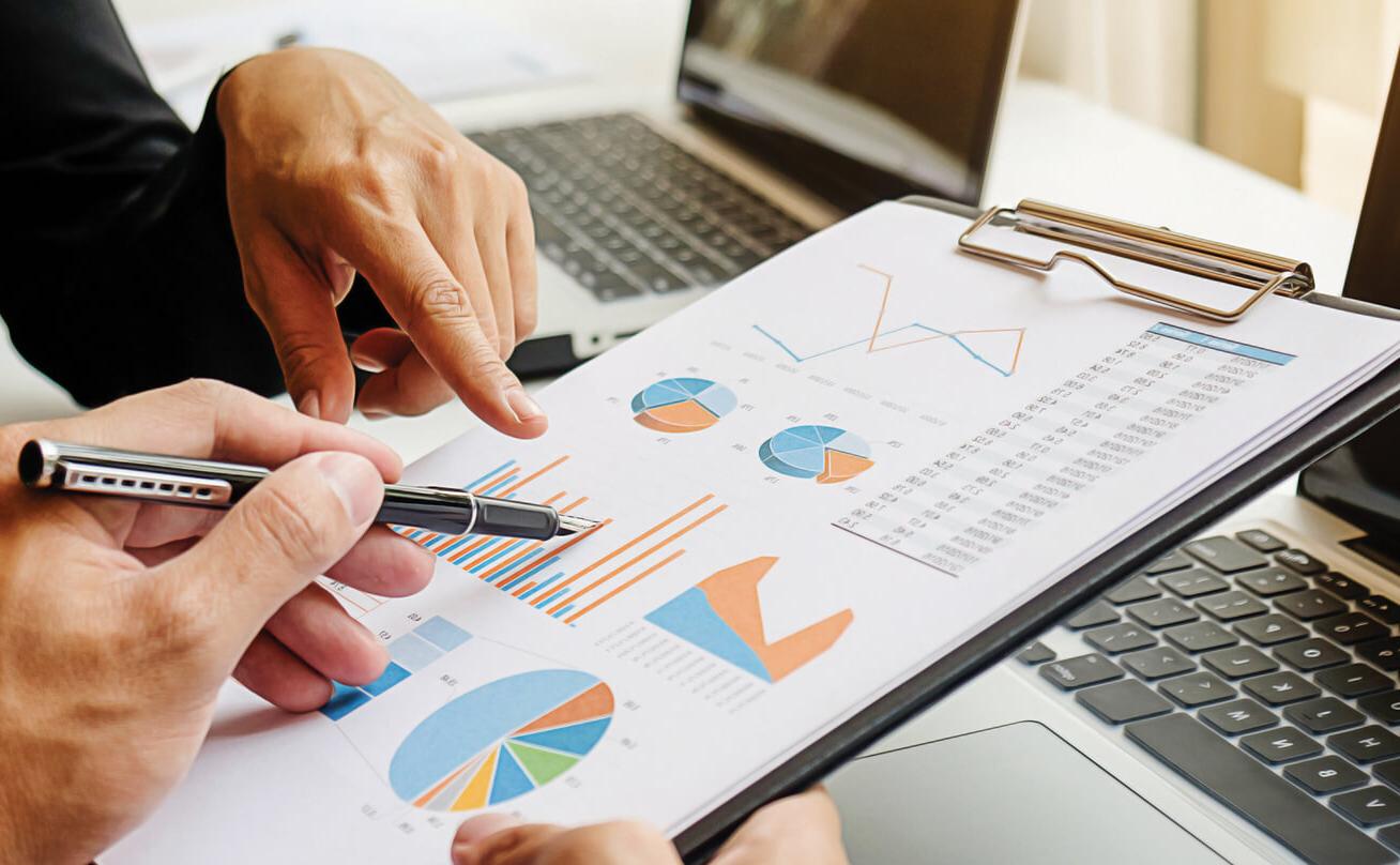 Hands pointing at clipboard with chart graphics