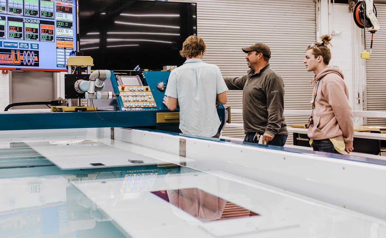 Two students working with professor at large piece of testing equipment